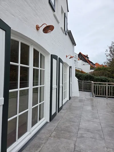 Twee wandarmaturen aan een witte gevel met terras