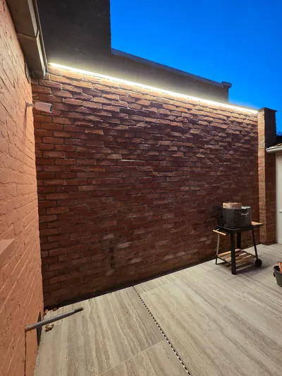 Lange lichtlijn langs de bovenrand van een bakstenen terrasmuur